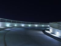 an empty parking lot at night with a sky background, and several lights on a walkway