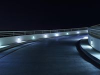 an empty parking lot at night with a sky background, and several lights on a walkway