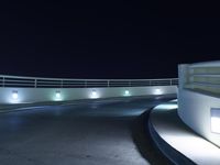 an empty parking lot at night with a sky background, and several lights on a walkway