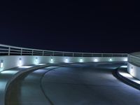 an empty parking lot at night with a sky background, and several lights on a walkway