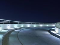 an empty parking lot at night with a sky background, and several lights on a walkway