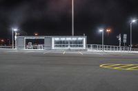 an empty parking lot at night with many lights and benches around it as well as multiple lamps