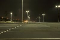 a empty parking lot with several lights shining in the dark sky, surrounded by trees and a few street lamps