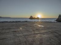 an empty parking lot overlooking the ocean and rock formations, at sunset time with sunlight coming through