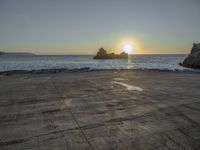 an empty parking lot overlooking the ocean and rock formations, at sunset time with sunlight coming through