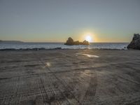 an empty parking lot overlooking the ocean and rock formations, at sunset time with sunlight coming through