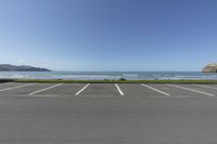 empty parking lot with the ocean and mountains in the background along an oceanfront drive