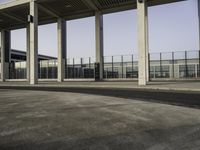 there is an empty parking lot with an open building behind it and cars in the distance