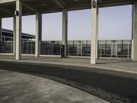 there is an empty parking lot with an open building behind it and cars in the distance