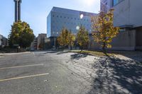 this is an empty parking lot with trees in front of a building and one street