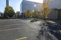 this is an empty parking lot with trees in front of a building and one street