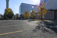 this is an empty parking lot with trees in front of a building and one street