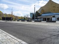 the parking lot is empty outside of the modern building and next to the street lined with stone benches