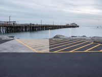 an empty parking lot with a pier in the background on a rainy day at dusk