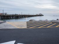 an empty parking lot with a pier in the background on a rainy day at dusk