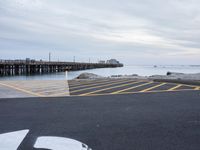 an empty parking lot with a pier in the background on a rainy day at dusk