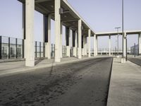 this image shows an empty area of a parking lot with pillars, the sky and street lights