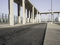 this image shows an empty area of a parking lot with pillars, the sky and street lights