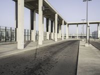 this image shows an empty area of a parking lot with pillars, the sky and street lights