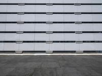 empty parking lot with one red sign in the center of it and two white buildings in the background