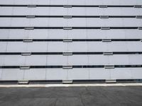 empty parking lot with one red sign in the center of it and two white buildings in the background