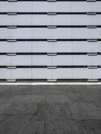 empty parking lot with one red sign in the center of it and two white buildings in the background