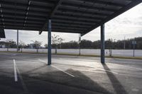 a empty parking lot with empty car spaces on it's sides and large metal poles