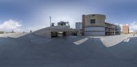 a skate board ramp on an empty asphalt parking lot, with a skateboard in the middle