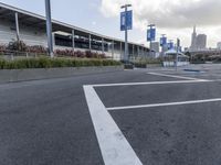 an empty parking lot with a fire hydrant near by and an elevated building to the right