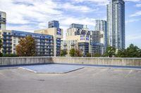 a parking lot that has an empty space with a skate board in it with many buildings behind it