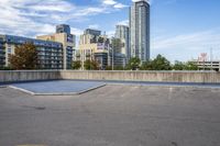 a parking lot that has an empty space with a skate board in it with many buildings behind it