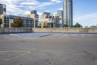 a parking lot that has an empty space with a skate board in it with many buildings behind it