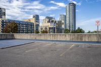 a parking lot that has an empty space with a skate board in it with many buildings behind it