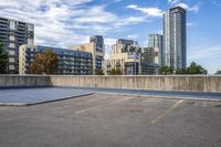a parking lot that has an empty space with a skate board in it with many buildings behind it