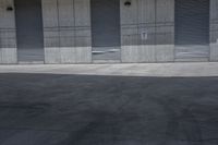 a skate board is in the middle of an empty parking lot outside a building with shutters to allow in some space