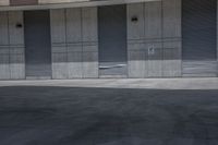 a skate board is in the middle of an empty parking lot outside a building with shutters to allow in some space