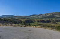 empty parking lot in front of steep mountain area on clear sunny day with blue sky