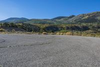 empty parking lot in front of steep mountain area on clear sunny day with blue sky