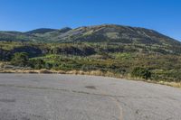 empty parking lot in front of steep mountain area on clear sunny day with blue sky