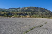 empty parking lot in front of steep mountain area on clear sunny day with blue sky