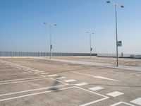 empty parking lot and street lamps along a sidewalk with blue skies above it's surface