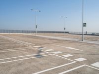 empty parking lot and street lamps along a sidewalk with blue skies above it's surface