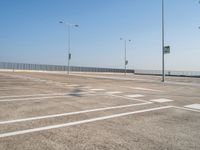 empty parking lot and street lamps along a sidewalk with blue skies above it's surface