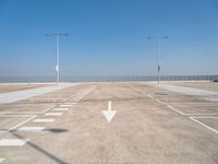 an empty parking lot with two street lights on the top of each pole on a sunny day