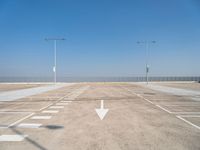 an empty parking lot with two street lights on the top of each pole on a sunny day