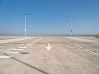 an empty parking lot with two street lights on the top of each pole on a sunny day