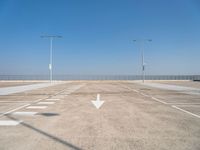 an empty parking lot with two street lights on the top of each pole on a sunny day