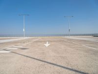 an empty parking lot with two street lights on the top of each pole on a sunny day