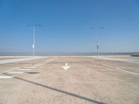 an empty parking lot with two street lights on the top of each pole on a sunny day