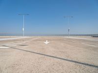 an empty parking lot with two street lights on the top of each pole on a sunny day